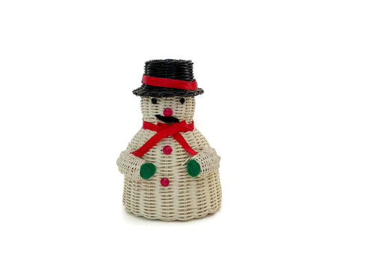 A small snowman-shaped decorative basket made from woven natural wicker, with a black hat, red hatband, red scarf, green buttons, and a pink nose, shown on a plain white background.