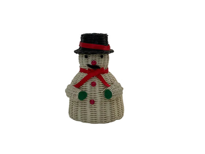 A small snowman figurine made from woven natural wicker, featuring a black top hat with a red band, a red scarf, green buttons, and a red nose, set against a plain white studio background.