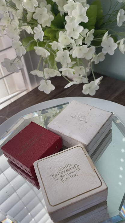 antique jewelry boxes on a reflective surface with flowers in the background